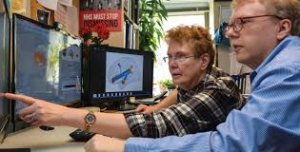 Marcie Zinn sitting at a computer, pointing something out to a colleague.