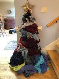 A pile of laundry is gathered into a Christmas tree shape with a star added at the top and the color changes in the laundry give the appearance of garland.