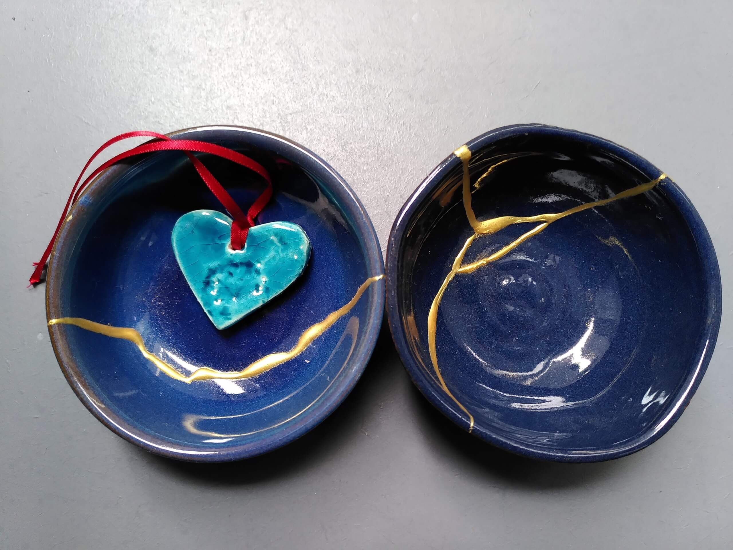 A clay heart in a blue bowl next to a similar blue bowl