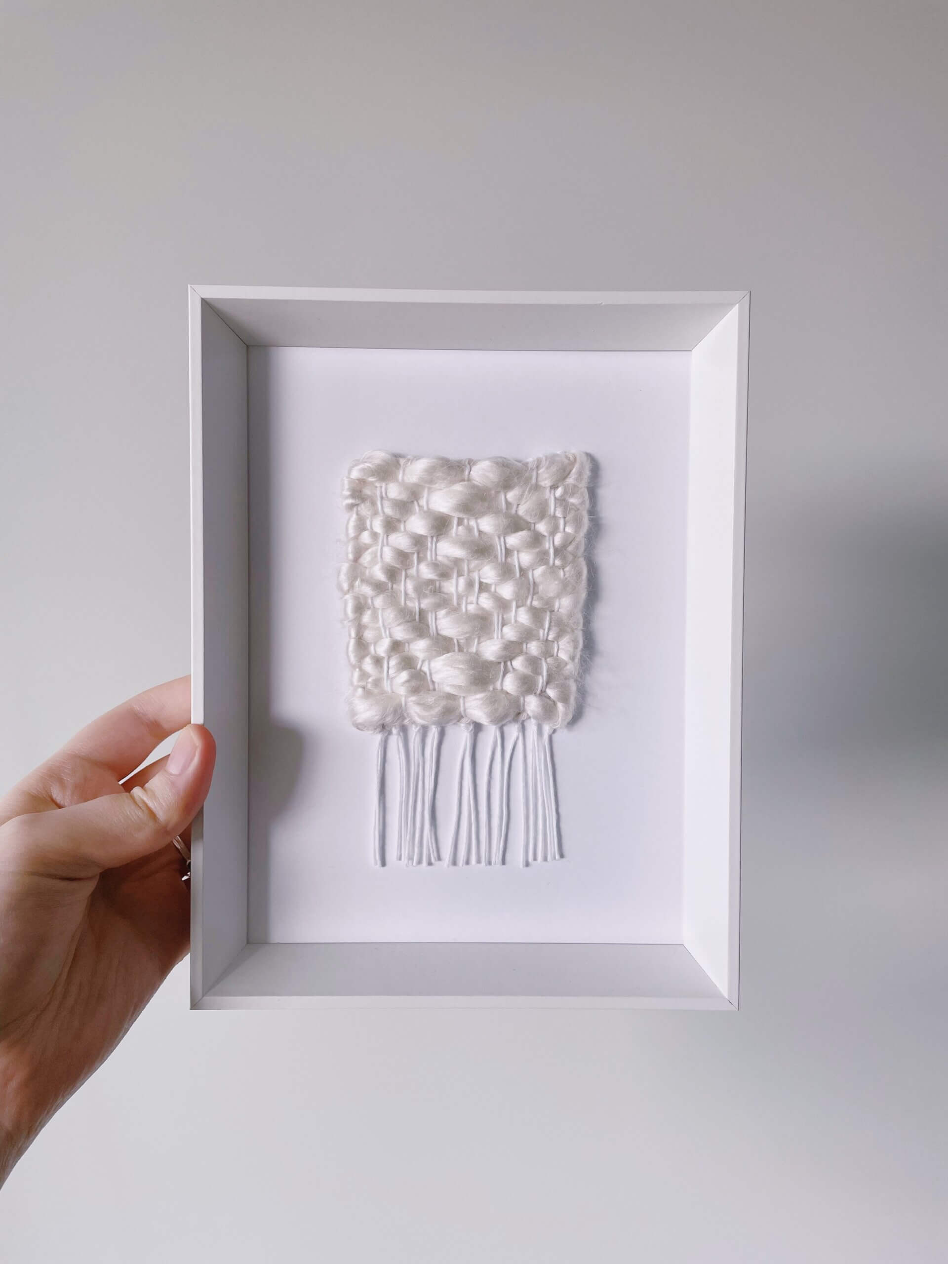 A white knitted square that is framed