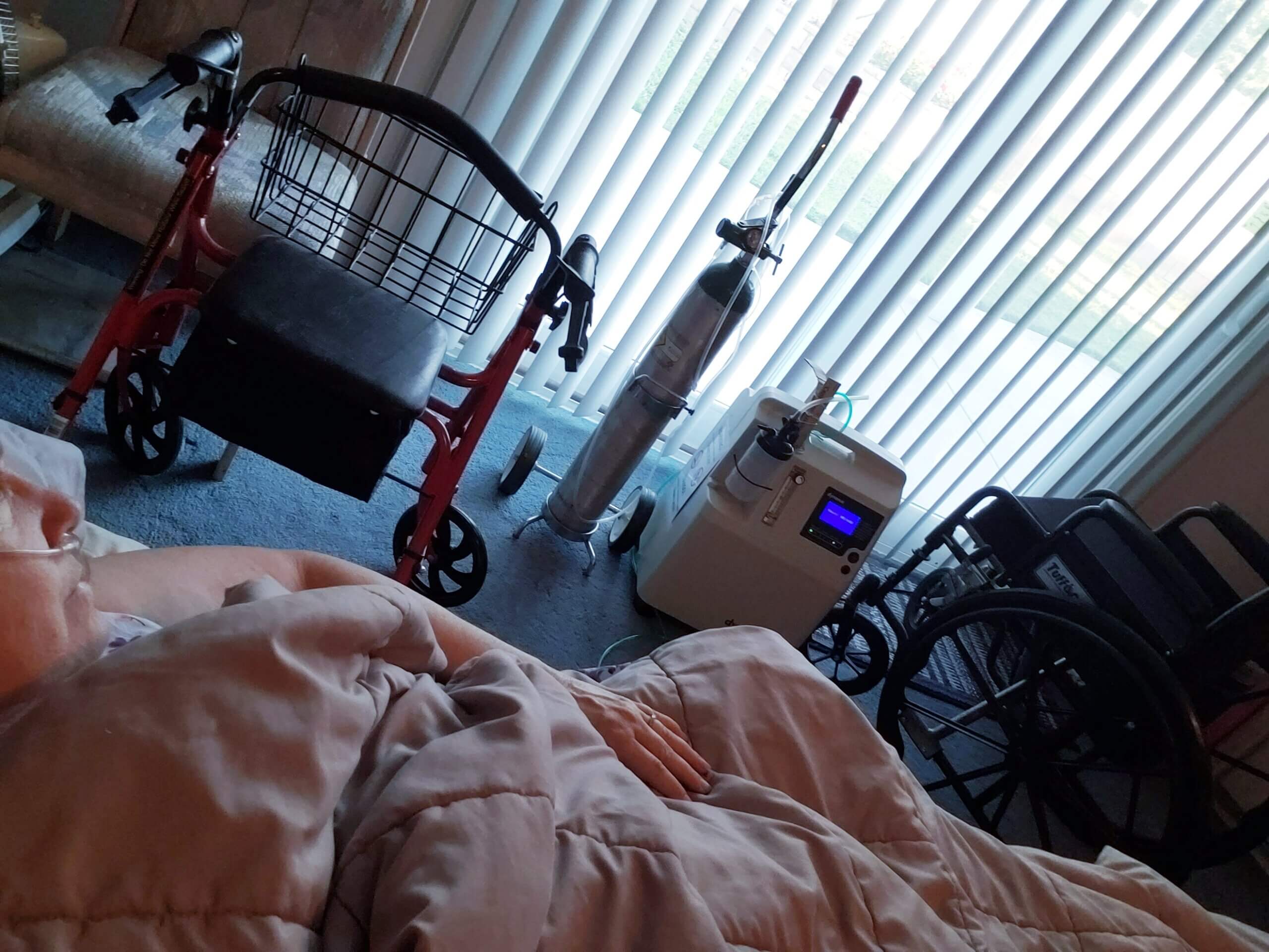 A photo of someone's walker, oxygen tank, wheelchair, and window