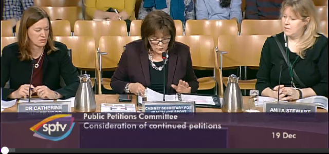 Three members seated and speaking at the Public Petitions Committee Meeting