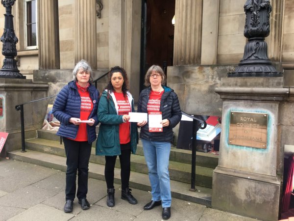 Three ME Action volunteers standing outside the Royal College of Physicians Edinburgh. They are holding leaflets and an addressed envelope.